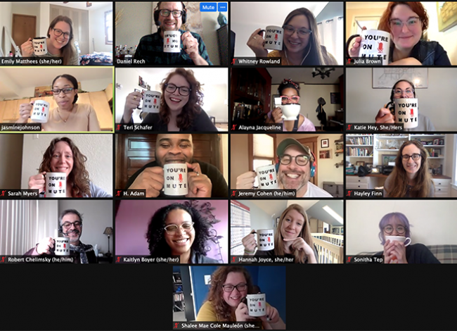 A screen cap of a Zoom meeting. Many staff members are holding coffee mugs next to their face. The mugs have text on them. "You're on Mute"